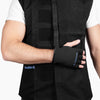 Close-up side view of a man wearing the Shoulder It vest, showing his arm bent and hand resting comfortably across his body using the built-in glove and strap. The product helps shoulder surgery patients sleep better by reducing pressure points from traditional slings.
