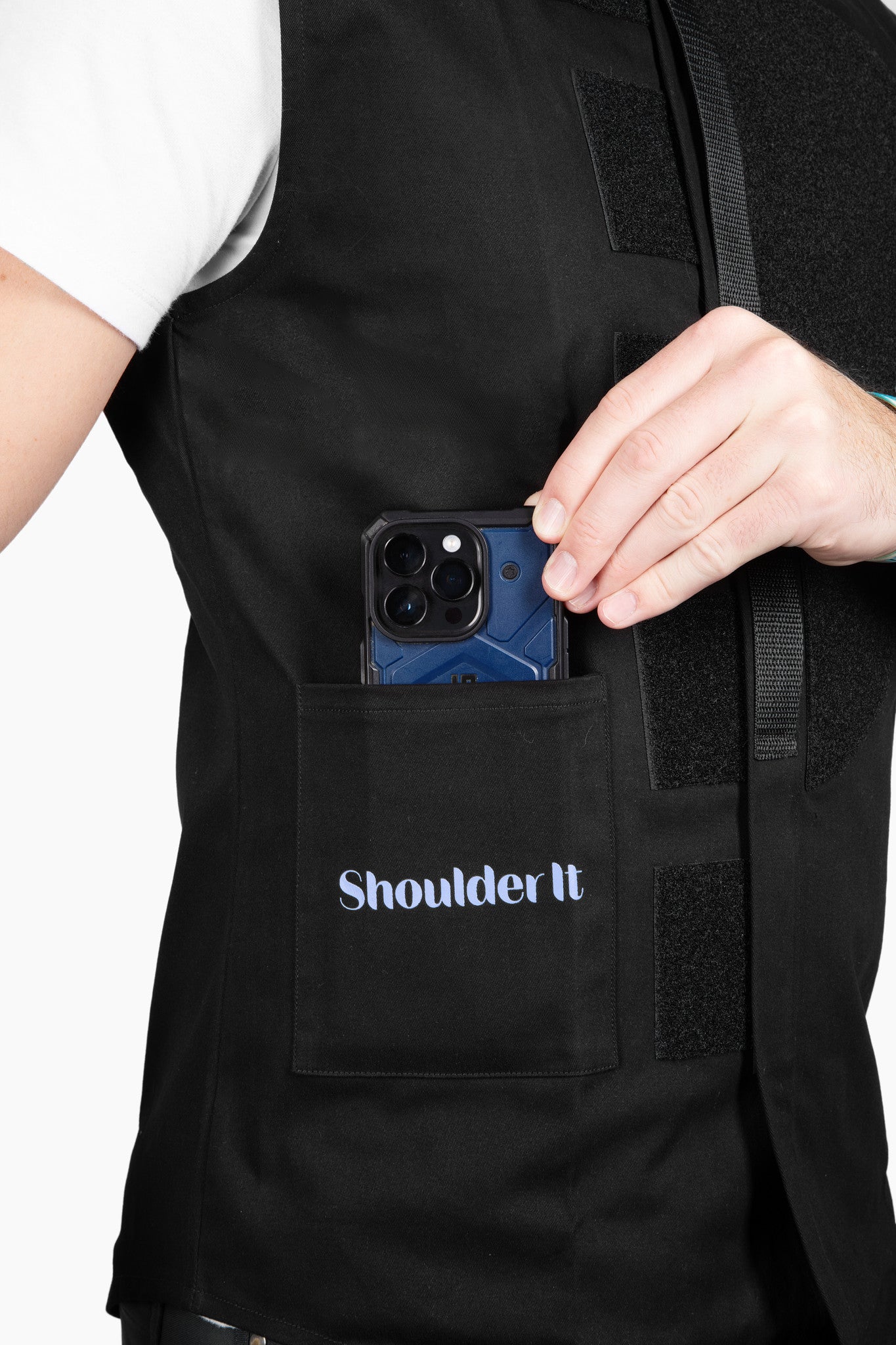 Close-up of a phone being placed into the front pocket of the Shoulder It vest. The vest includes functional pockets for easy access to essentials, offering added convenience during shoulder surgery recovery.The vest's minimalist design supports pain-free rest for people recovering from shoulder procedures.