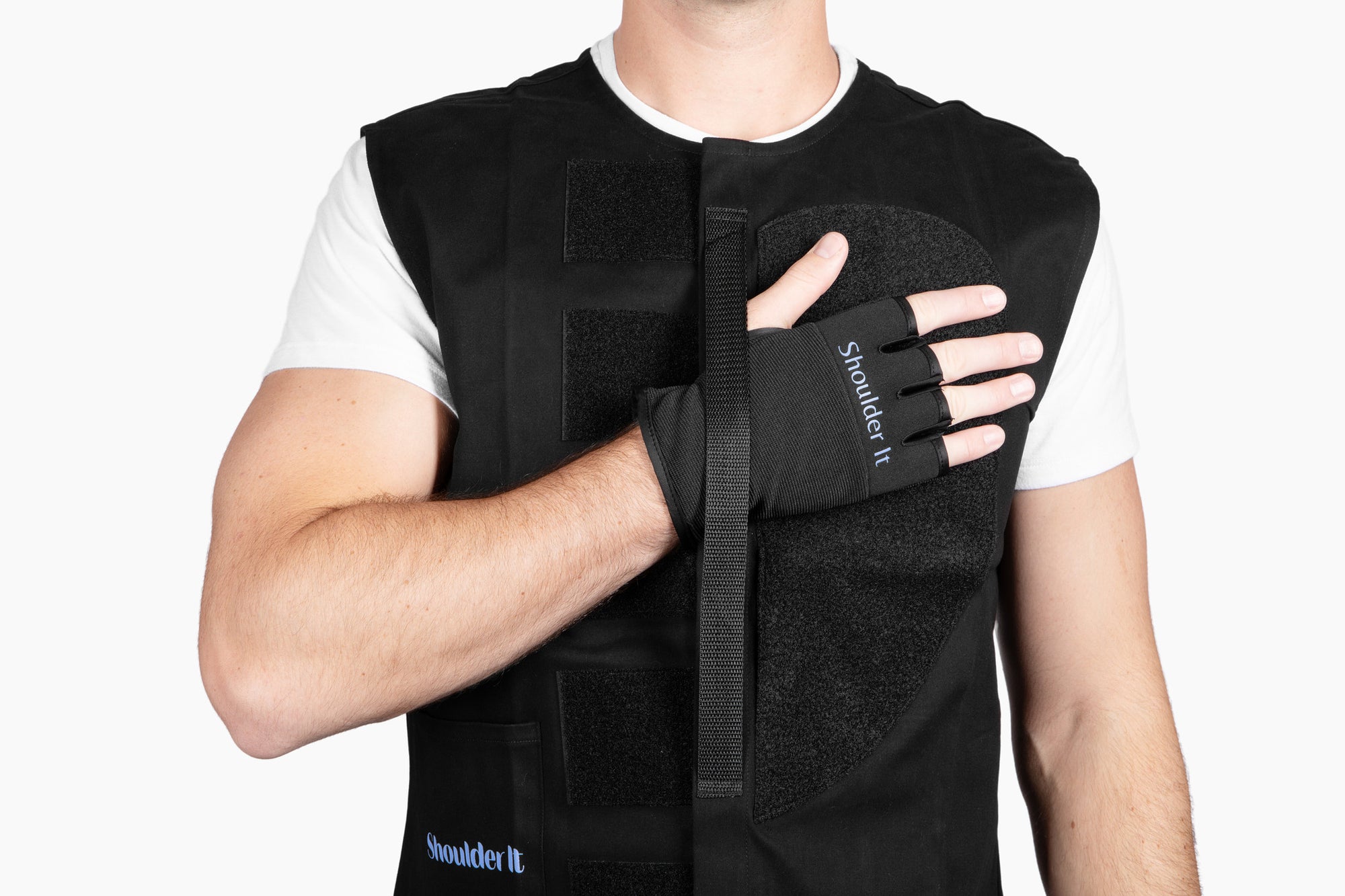 Detailed shot of the Shoulder It glove attachment with visible branding. The hand is held in place across the padded vest panel, demonstrating the vest's secure yet adjustable design ideal for sleeping after shoulder surgery such as rotator cuff or labral repair.